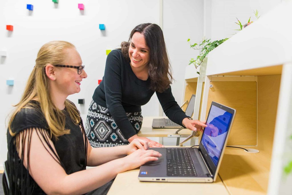 Docent legt Nederlandse grammatica op computer uit aan student